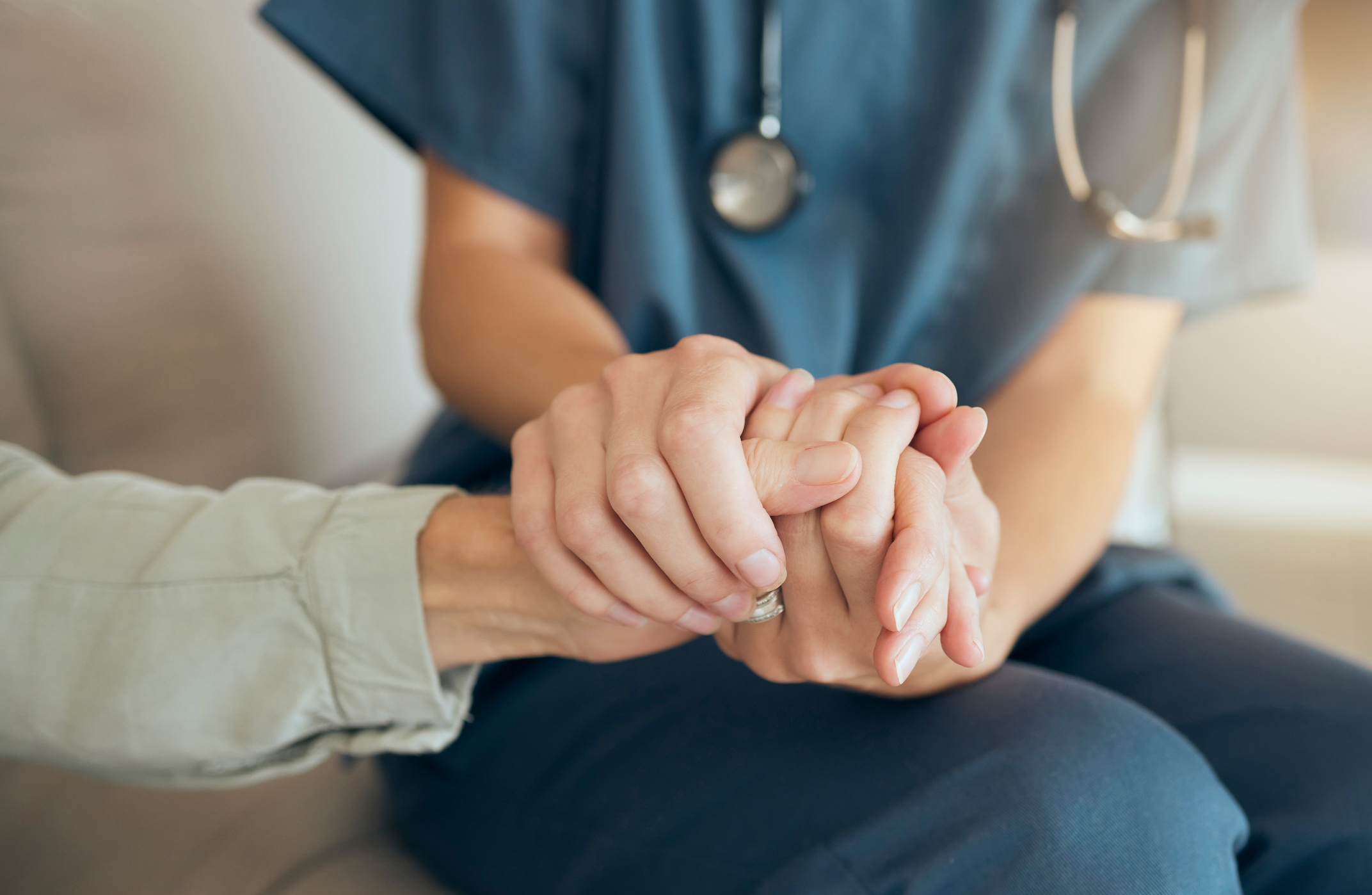 Nurse holding patient's hand with compassion during diagnosis